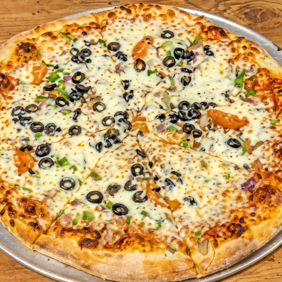 A whole vegetarian pizza with black olives, green peppers, and tomatoes on a wooden table.